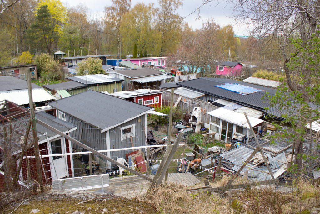 En översiktsbild av området som är tagen lite uppifrån. På bilden syns hustak, de flesta i plåt och några i trä. Husen har olika färger.