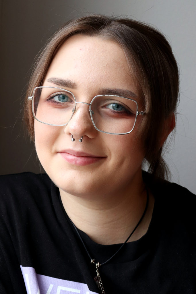 Ett portätt på Alva Flodwall. Hon har septum och rundade silvriga glasögon.